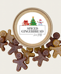 A round wooden gift tin labeled 'Spiced Gingerbread' with a white center label and small holiday illustration, surrounded by several gingerbread-shaped cookie wax melts in light brown, medium brown, and dark chocolate tones on a light beige background.