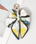 Decorative bow keychain with floral pattern with yellows and blues on a light background