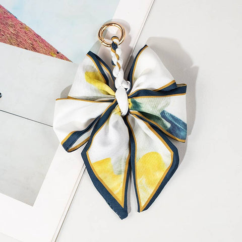 Decorative bow keychain with floral pattern with yellows and blues on a light background