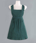 Green pinafore apron on a mannequin against a gray background