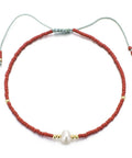 Bracelet with red beads and a pearl on a white background