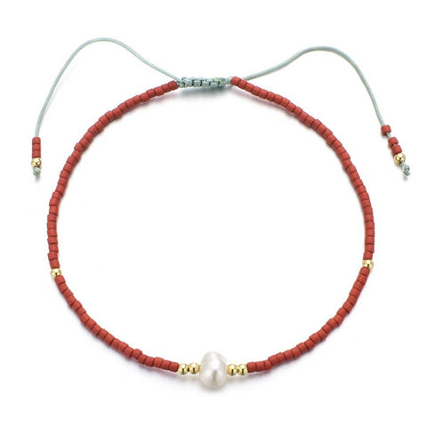 Bracelet with red beads and a pearl on a white background