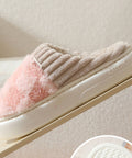 Pair of beige and pink slippers on a white surface with a neutral background