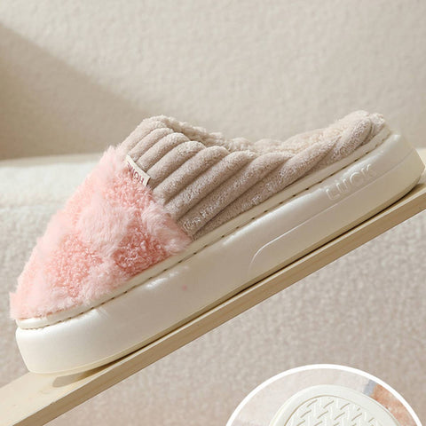 Pair of beige and pink slippers on a white surface with a neutral background