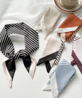 Collection of patterned scarves on a white surface with a cup and saucer.
