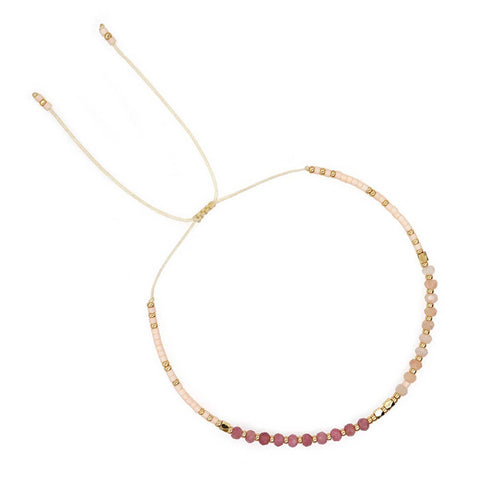 Bracelet with pink and gold beads on a white background