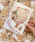 gingerbread house holiday card with candy looking stickers for decorating the gingerbread house on a background of sugar cookies