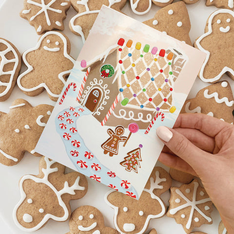 gingerbread house holiday card with candy looking stickers for decorating the gingerbread house on a background of sugar cookies