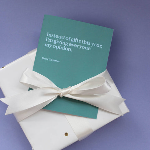 the gift of snark this season greeting card pale blue on green background tied with cream bow