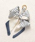 Navy and white striped bow keychain on a textured beige background