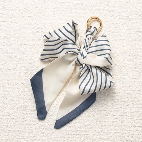 Navy and white striped bow keychain on a textured beige background