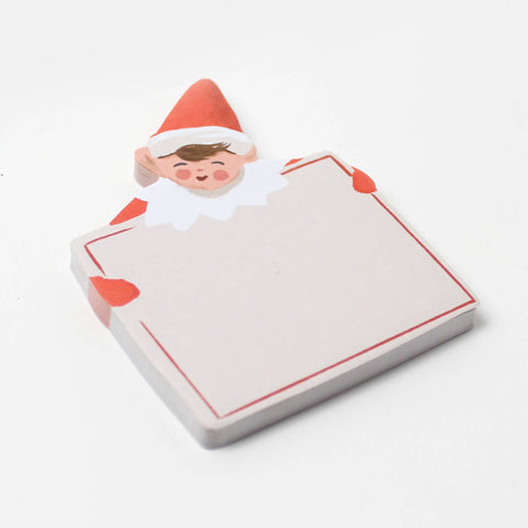 sticky note pad shaped like holiday elf holding large card. elf is dressed in red on green background board