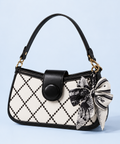 A black and white patterned handbag with a black leather handle, a snap-button closure, and a decorative black-and-white patterned bow, shown on a light blue background.