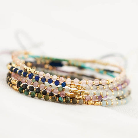 Stack of colorful beaded bracelets on a light background