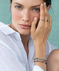 Woman wearing small beaded jewelry with a light green background