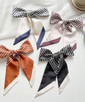 Five striped scarves tied into bows on a white surface.