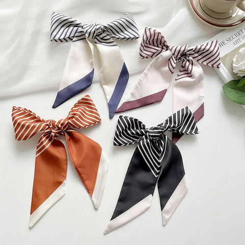 Five striped scarves tied into bows on a white surface.