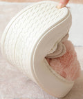 White shoe with pink interior being held by a hand on a light background bending to show flexibility.