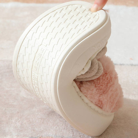 White shoe with pink interior being held by a hand on a light background bending to show flexibility.