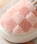 Close-up of a pink fluffy pet bed with a brand label on a soft surface.