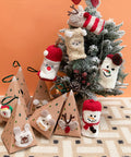 Decorative Christmas tree with animal-themed ornaments and gift boxes on a patterned surface.